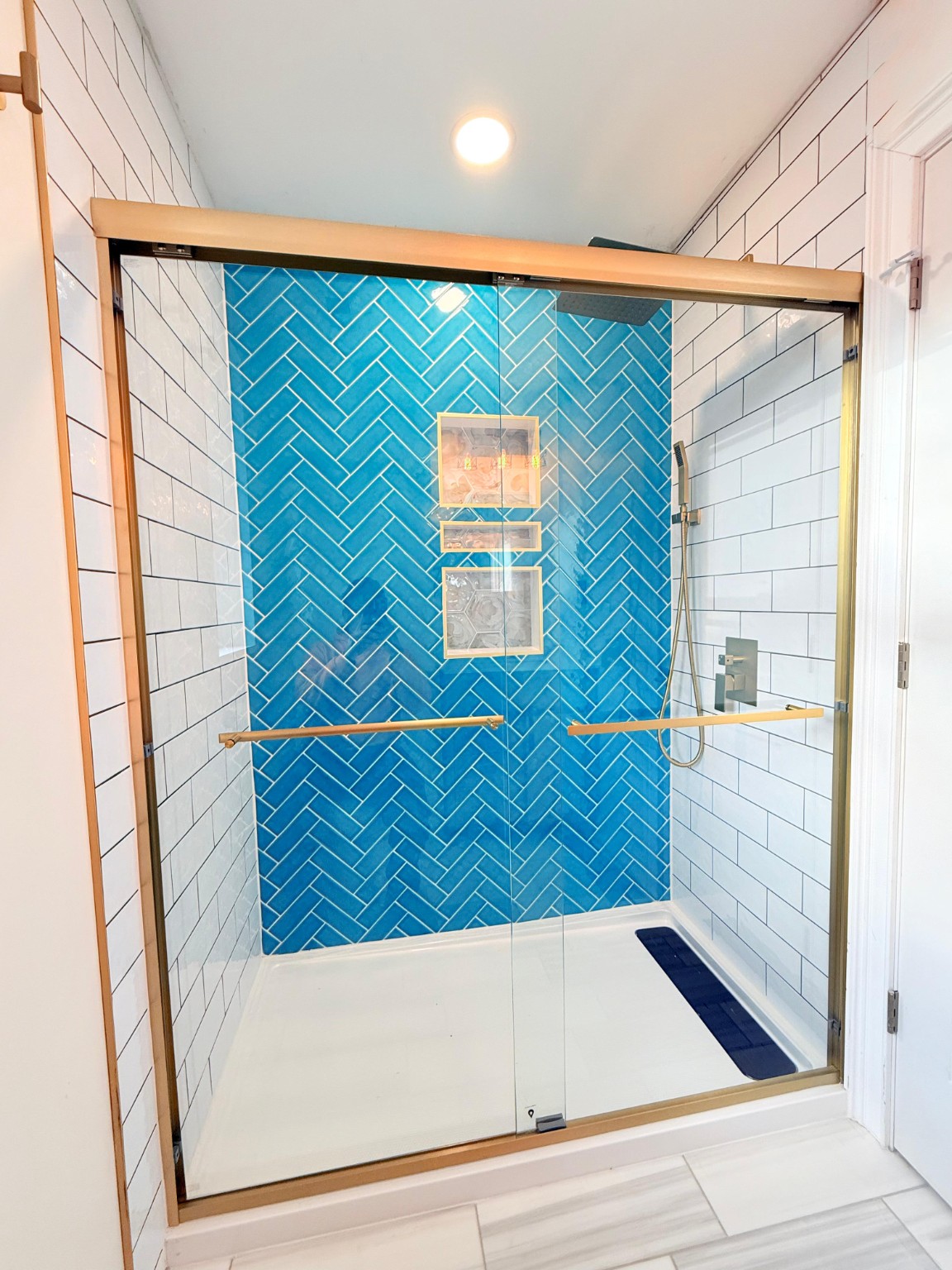 Walk-in shower with blue herringbone accent tile and glass enclosure