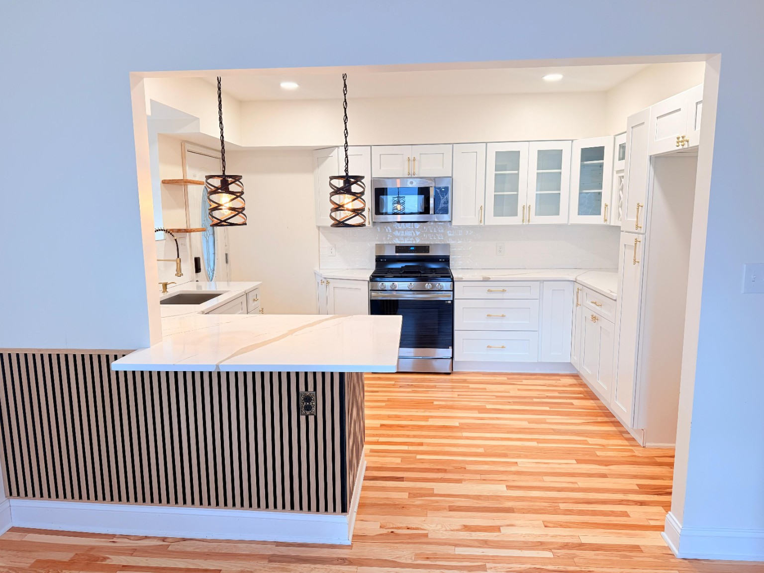 Open-concept white kitchen remodel with peninsula and hardwood floors